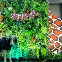 A wild jungle theme for a first birthday. We created a dense green wall of tropical leaves with a custom wooden "Avyay is One" sign, complete with animal props to bring the safari to the party.