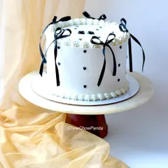 A side view of the classic vintage cake, showing the delicate black ribbon bows and heart details on the smooth white buttercream.