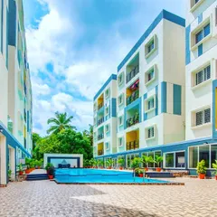 The central courtyard and swimming pool area of a group housing project. The use of blue and yellow accents on the building facades adds a playful and vibrant character to the community space.