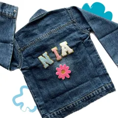 A simple and cute custom denim jacket for a girl named "Nia," featuring her name and a flower patch.