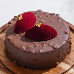 Our Belgian Chocolate and Hazelnut Fudge cake, cloaked in a glossy rocher glaze and topped with delicate red velvet accents. This is a masterpiece of fudgy, crunchy, can’t-stop magic.