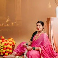 A beautiful studio portrait in a traditional Maharashtrian style. The bright pink nauvari saree, flower garland, and classic props create a timeless and culturally rich image.