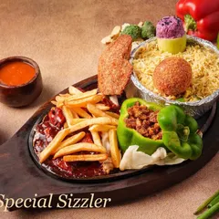 Our Chef Special Sizzler is a complete meal. It includes flavourful rice, a vegetable cutlet, fries, and a stuffed capsicum, all served on a sizzling hot plate with our special sauce.
