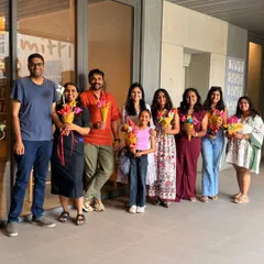 A smiling group of participants, including adults and a child, pose together holding the beautiful origami flower bouquets they created during our workshop. These sessions are great for all ages and leave everyone with a handmade treasure.