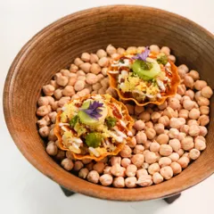 Our take on chaat, served in a crisp canapé shell over a bed of chickpeas. It’s a burst of tangy, sweet, and savoury flavours, finished with an edible flower for a touch of elegance.