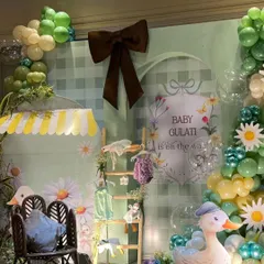 A close-up of the whimsical duck-themed baby shower decor. The setup includes a gingham backdrop, daisy accents, and a cute duck prop.
