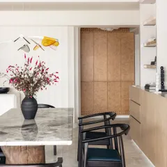 The dining area flows seamlessly from the entrance, with soft, raw cotton hues on the walls creating a calming backdrop. Pops of color and subtle accents reflect the personalities of the family members.