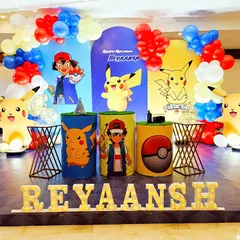 Gotta catch 'em all with this exciting Pokemon birthday theme. The stage is set with Ash and Pikachu character cutouts, themed plinths designed like Poke Balls, and balloon columns in the classic red, yellow, and blue colors.