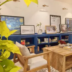 Another view of the custom blue bookcase, showcasing how my clients' art collection is thoughtfully displayed. The picture lights above highlight each piece, turning the wall into a personal gallery.
