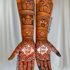 This is a full bridal mehendi design that blends devotion with intricate traditional patterns. The palms feature "Siya Ram" and "Radha Krishna" in beautiful calligraphy, surrounded by auspicious symbols like the kalash, Om, and swastika, extending up the forearms.