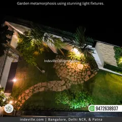An aerial view of a backyard I designed, captured at night. The strategic lighting highlights the winding stone pathway, the different plant textures, and the overall layout, turning the garden into a magical nighttime wonderland.