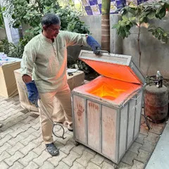 I am opening the glowing hot Raku kiln, ready to remove the pottery. This is a critical moment in the dramatic and fast-paced firing process.