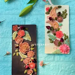 My artisanal chocolate bars are edible art. This photo shows both the dark and white chocolate options, decorated with intricate, hand-piped floral patterns and paisley designs.