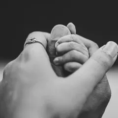 A black and white photo showing a newborn's hand holding onto their parent's fingers. This classic shot emphasizes the new and powerful connection within the family.