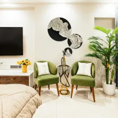 A cozy seating corner within a bedroom, featuring olive green armchairs and unique wall art. I believe in creating multi-functional bedrooms that offer spaces for both rest and relaxation.