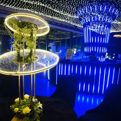 A modern floral centerpiece with an integrated light fixture, set against the glowing blue bar, showcasing our blend of contemporary design and classic elements.