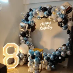 A modern and stylish setup for an 8th birthday, using a cool palette of black, silver, and metallic blue. The decoration features a full balloon ring, a neon sign, and a large light-up number '8'.