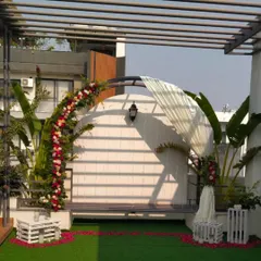 The same terrace setup during the day, showing the lush floral arch made of red, pink, and white roses against a white backdrop.
