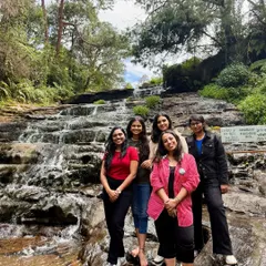 A group of friends posing by a beautiful tiered waterfall in Kodaikanal.