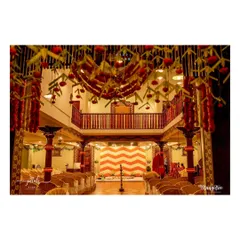 The main hall at Ganjam Mantapa decorated for a naming ceremony. The ceiling features a beautiful installation of hanging flowers, and the stage has a vibrant chevron-patterned backdrop.