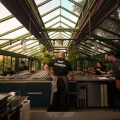 This is the view from the pass, my favorite spot in the house. It captures the essence of what we do: a chef, ready to perform, looking out at the intimate, sunlit stage of our glasshouse before the guests arrive.