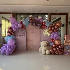 A "We can Bearly wait" baby shower setup in shades of lavender, blue, and rose gold, featuring a custom backdrop, neon sign, and teddy bear props.