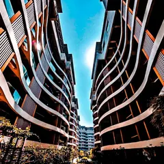 An upward view of the Palm Bellagio's wave-inspired facade in Raipur. The flowing curves of the balconies create a sense of movement, breaking the monotony of a typical residential block and establishing a unique architectural identity.