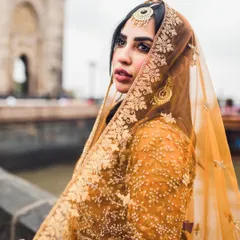 A stunning bridal portrait with the Gateway of India in the background. The bride's expression and the way she holds her embroidered dupatta create a look of timeless elegance.