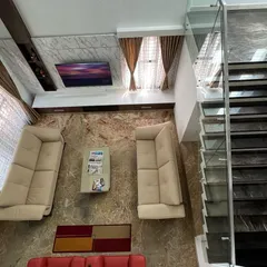 A top-down view of a living area in the 'Hongirana' project, showing the arrangement of furniture on a richly patterned marble floor next to a modern staircase.
