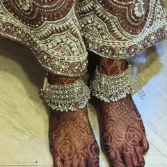 The beautiful henna stain on the bride's feet, perfectly complemented by her silver payal (anklets).