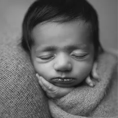A close-up in classic black and white, focusing on the serene expression of a sleeping newborn. Every tiny feature, from the eyelashes to the lips, is preserved forever.