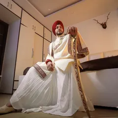 Preserving cultural richness, this portrait captures the Sikh groom in his traditional attire, holding a sword, looking regal and poised.