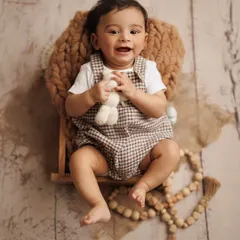 Look at that happy smile. This overhead shot captures the pure joy of a baby boy during his milestone session, using a simple setup with natural textures and a favorite toy.