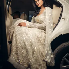 The bride makes a stunning entrance, stepping out of a car in her shimmering white lehenga. This shot feels like a scene from a movie, capturing her elegance and the anticipation of the night ahead.