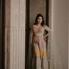 A stunning full-body portrait of the bride in her colorful sharara. The elegant pose and soft lighting beautifully showcase her unique and stylish pre-wedding outfit.