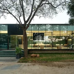 The VPG Experience Center at dusk. The transparent facade glows from within, acting as a lantern and a beacon on the busy Whitefield Main Road.