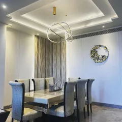 For this dining area, the goal was to create a space that feels both grand and intimate. The multi-layered tray ceiling with concealed lighting adds architectural depth, while the modern sculptural chandelier serves as a stunning centerpiece. The combination of a marble-top table, plush upholstered chairs, and subtle wall textures results in a luxurious setting for family meals.