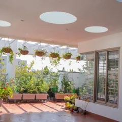 A sun-drenched terrace at 'Isha-Vaasyam', featuring circular skylights and a pergola that supports a lush collection of hanging plants, creating a vibrant urban garden.