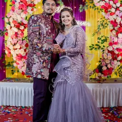 For a modern reception, I suggest this pairing. She is wearing a contemporary fish-cut lehenga gown in lavender, and he is in a richly embroidered maroon Indo-Western sherwani, creating a bold and stylish contrast.