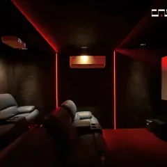 An immersive home theater experience with plush leather recliners, a large projection screen, and dramatic red ambient lighting that sets the mood for movie night.