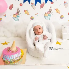 A wider view of the sweet treats-themed newborn session, showing the full setup with pink balloons, gift boxes, and a festive banner.