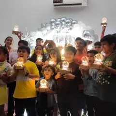 A room full of shining stars! The birthday crew proudly holds up the personalized light-up lamps they engineered themselves as the perfect party favor.