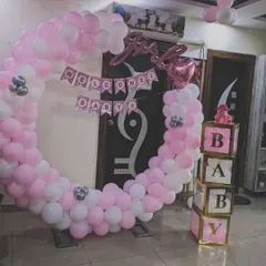 This welcome home setup for a baby girl features a full balloon ring in pink and white. The design is complemented by "It's a Girl" foil balloons and decorative "BABY" blocks for a complete look.