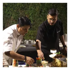 A moment of mentorship, as a senior chef guides a junior chef in plating, showcasing our culture of teamwork and excellence.