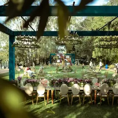 A beautiful long shot of the lakeside reception setup. The open-sided structure, adorned with greenery chandeliers, allowed guests to dine while enjoying the stunning natural surroundings.