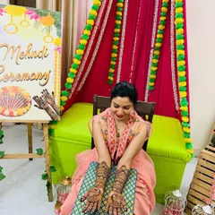 This client is all smiles at her home mehndi ceremony. We bring the complete professional setup to your location, making it a comfortable and stress-free experience for you and your family.