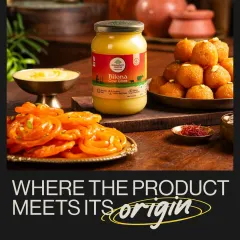 A jar of Organic India's Bilona Ghee surrounded by traditional Indian sweets like Jalebi and Ladoo. This composition shows the product in its cultural context, highlighting its use in festive and everyday cooking.