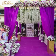 A bold and beautiful entrance in royal purple. The decor features rich purple draping, a carpet to match, and an abundance of white floral arrangements for a striking contrast.