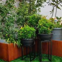 This terrace design uses a combination of corten steel planters and black pots on minimalist stands. The mix of artificial turf and varied planters creates a modern, multi-level garden space.
