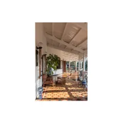 The sun-drenched verandah, with its restored geometric tile flooring and original columns, serves as a perfect transition between the interior and the lush surrounding landscape.